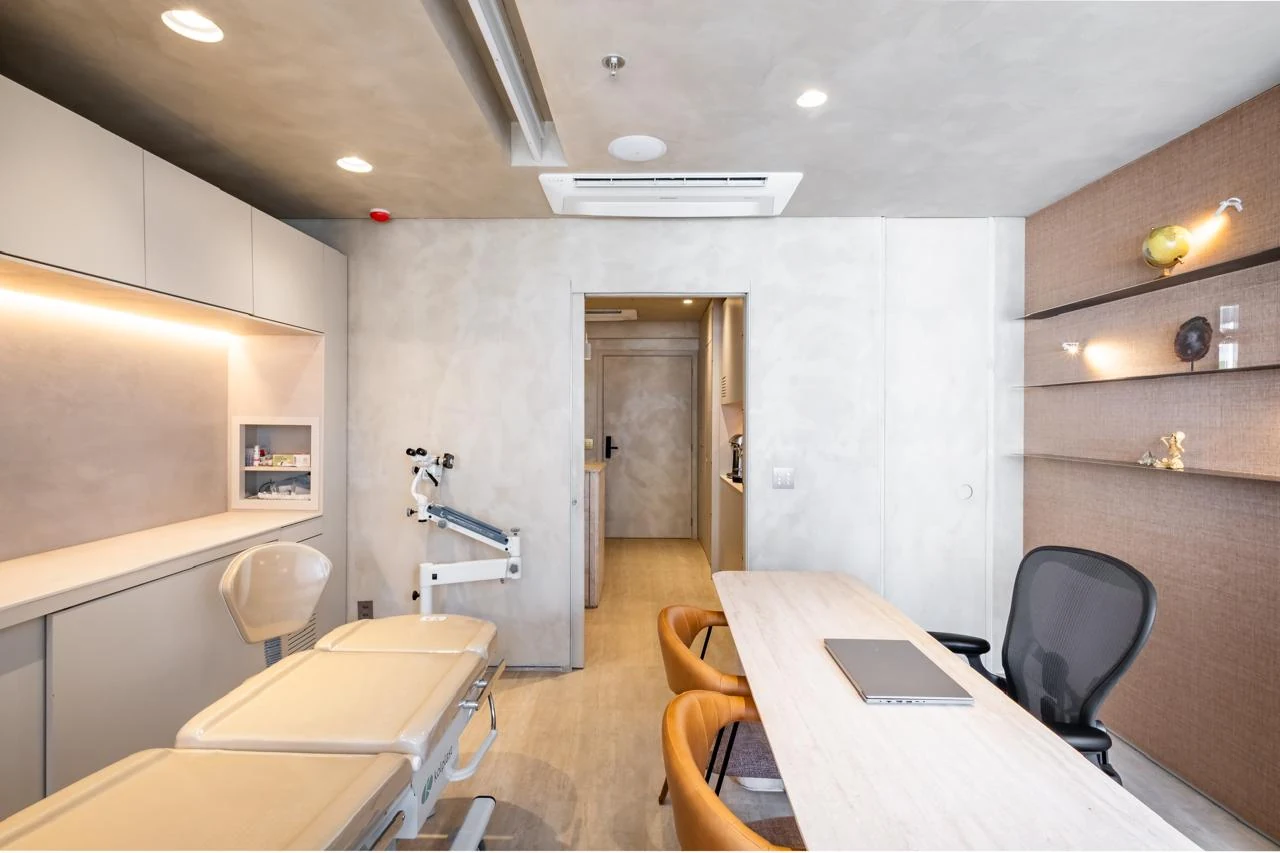 Sala da clínica com maca de exame e mesa de atendimento